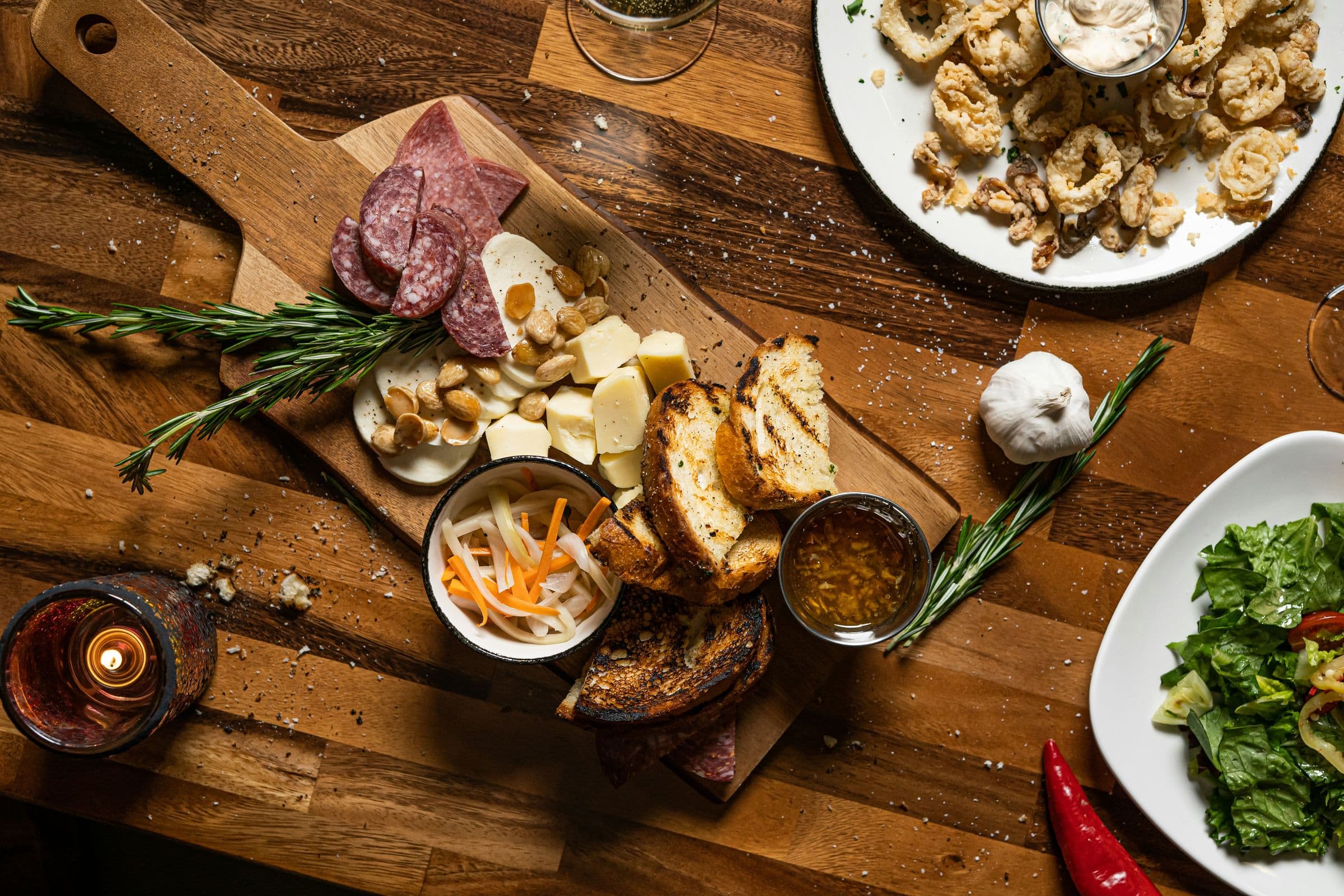 Tagliere con salumi, formaggi e pane su un tavolo di legno